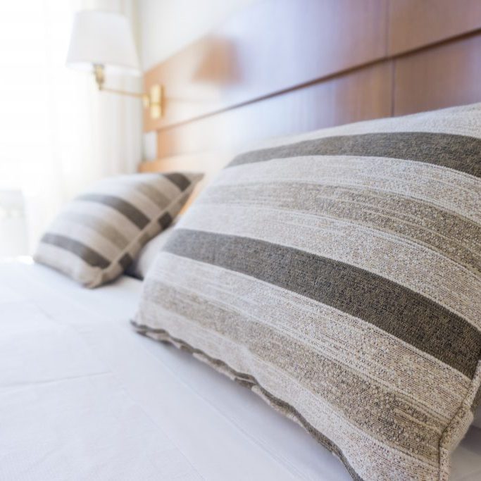 hotel bed with striped pillows and white sheets
